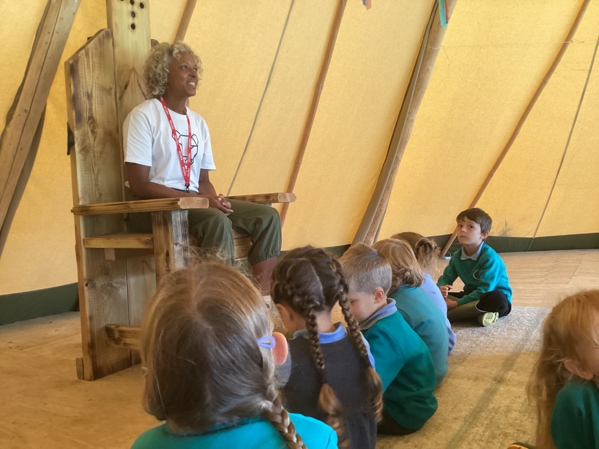 Children being read to insode a wooden Yurt